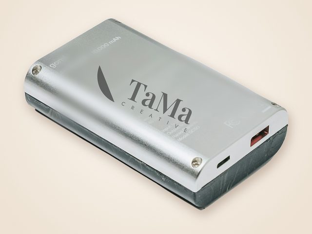 Mockup ilustrativo: power bank prata com a marca TaMa