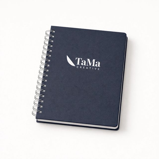 Agenda diária wire-o azul-marinho, fechada, com a marca TaMa em branco na capa.