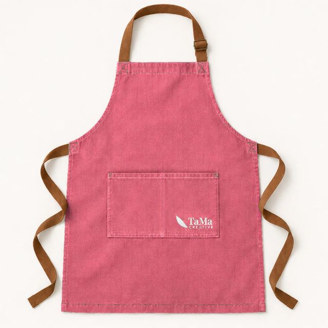 Avental com alças caramelo e bolso duplo, na cor rosa, com a marca TaMa no bolso.