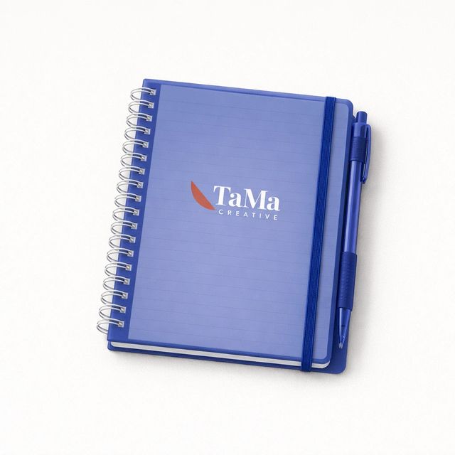 Bloco espiral com capa translúcida azul royal, elástico e caneta presa na lateral, com a marca TaMa em branco, folha em vermelho, na capa.