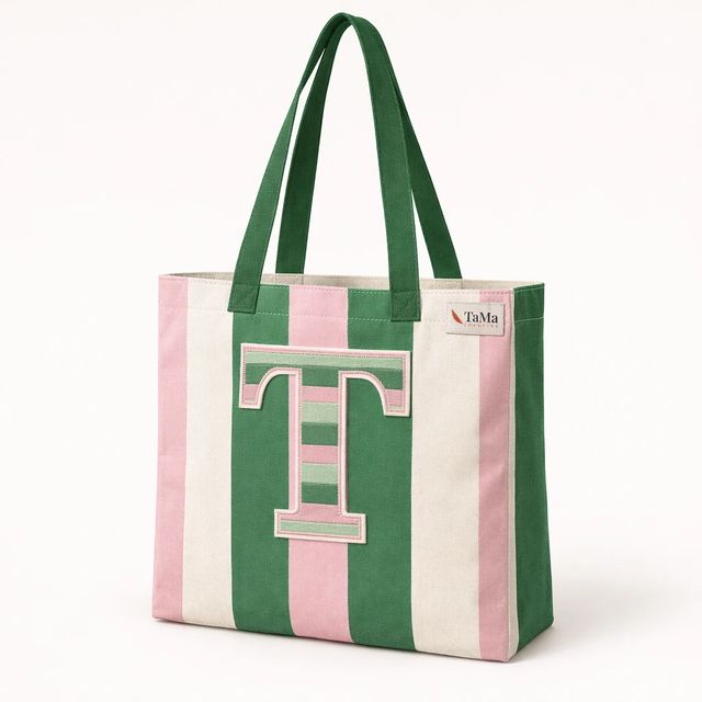 Bolsa com listras rosa e verdes, letra T aplicada na frente, alças verdes e etiqueta com a marca TaMa.
