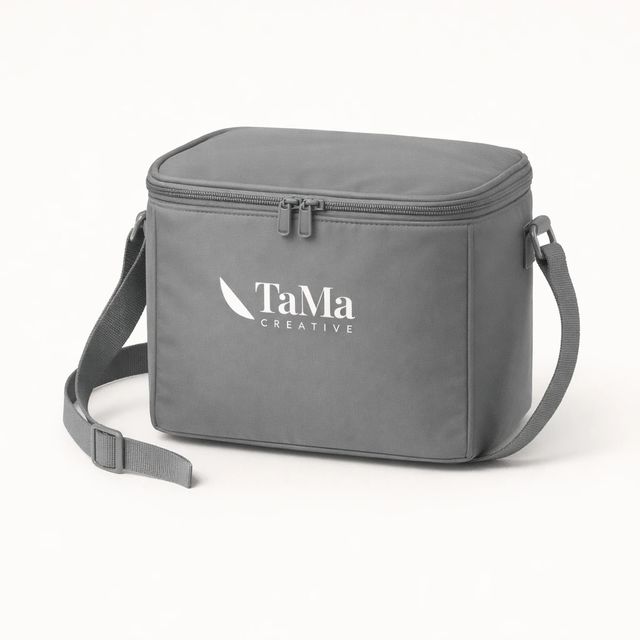 Bolsa térmica cinza com tampa de zíper, alça de ombro e a marca TaMa em branco na frente.