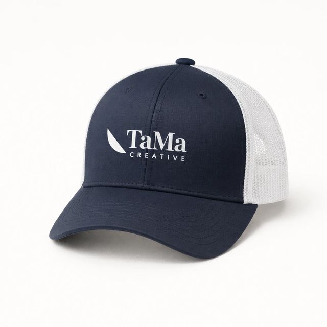 Boné trucker azul-marinho com frente lisa, tela branca atrás, aba curva e a marca TaMa em branco na frente.