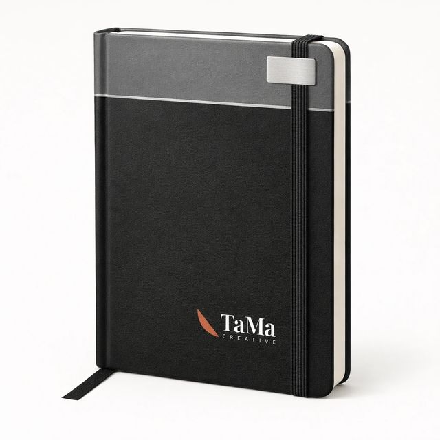 Caderno preto com faixa superior cinza, friso claro e plaquinha prata, com a marca TaMa em branco, folha em vermelho, na capa.