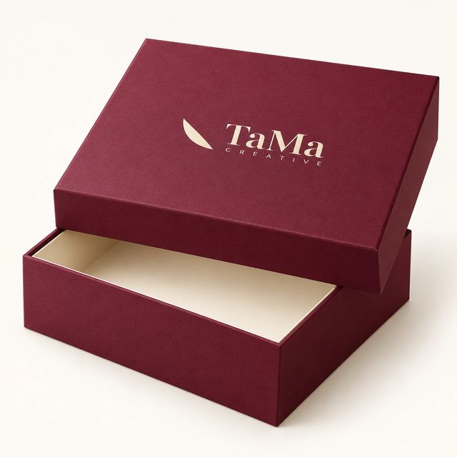Caixa rígida bordô com tampa e a marca TaMa em hot stamping dourado.