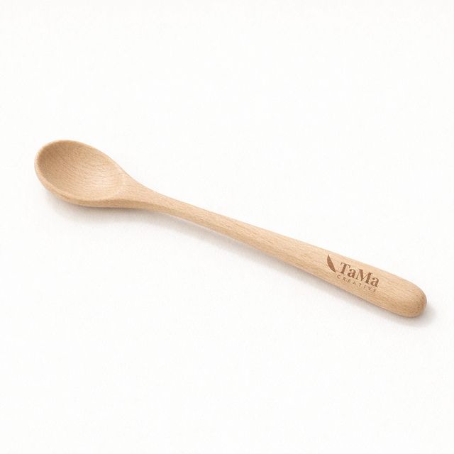 Colher pequena de cabo longo em tom natural, com a marca TaMa gravada no cabo.