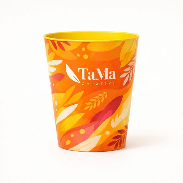 Copo com estampa abstrata laranja em toda a volta e interior amarelo, com a marca TaMa em branco na frente da estampa.