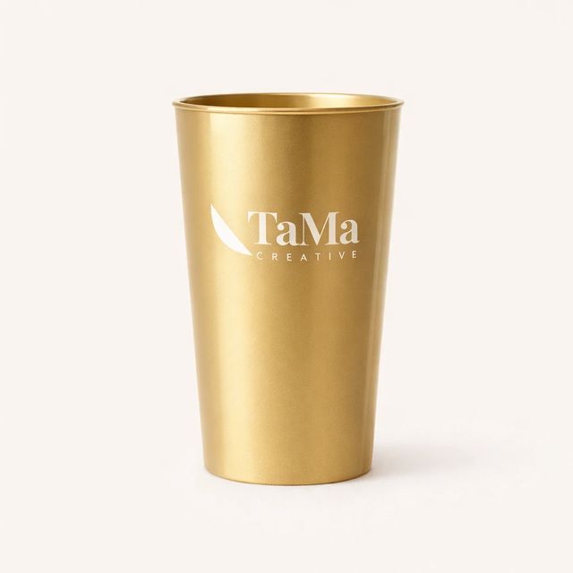 Copo long drink dourado com a marca TaMa em branco.