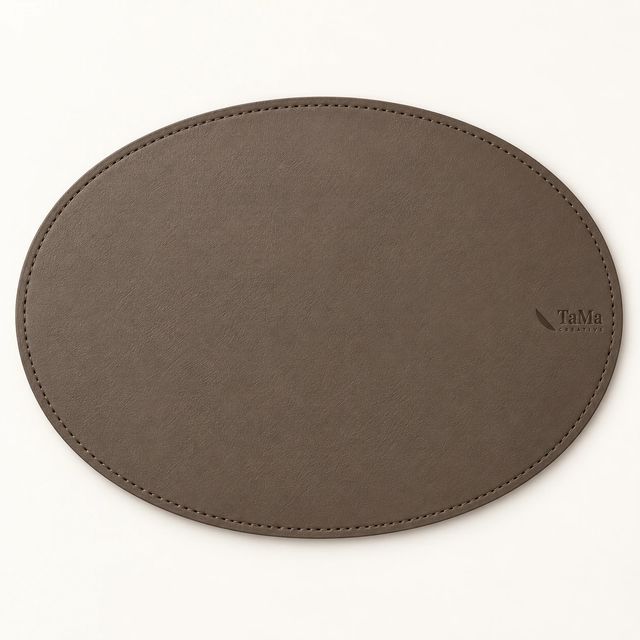 Jogo americano oval taupe com a marca TaMa em baixo-relevo.