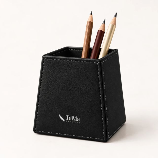 Porta-canetas com costura aparente, com lápis, na cor preta, com a marca TaMa na frente.
