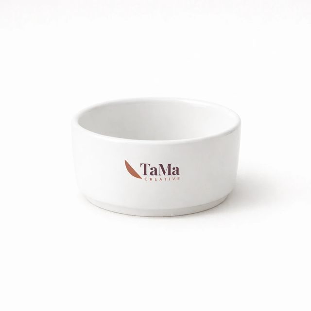 Ramequim branco redondo e vazio, com a marca TaMa nas cores oficiais na lateral.