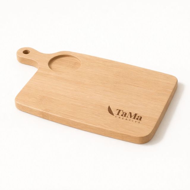 Tábua em tom natural com cabo vazado e rebaixo circular para copo, vazia, com a marca TaMa gravada no canto.