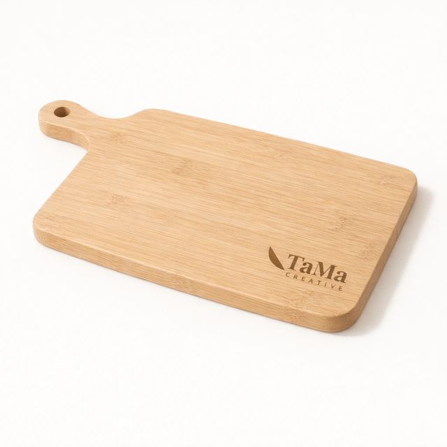 Tábua de petiscos em tom natural com cabo vazado, vazia, com a marca TaMa gravada no canto.