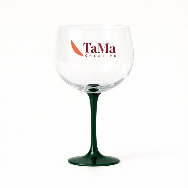 Taça de gin de bojo transparente e pé verde, com a marca TaMa no bojo.