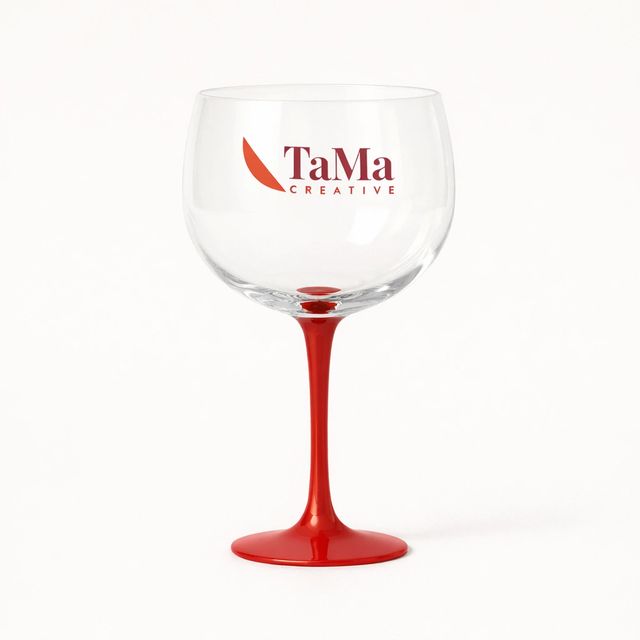 Taça de gin de bojo transparente e pé vermelho, com a marca TaMa no bojo.
